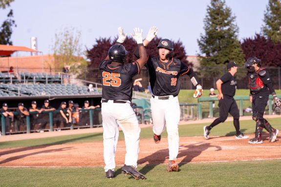 The Pacific baseball team celebrates scoring.