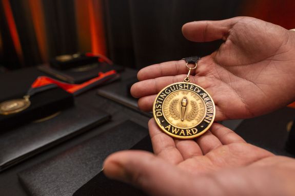 Hands holding a distinguished alumni medallion