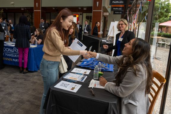 Two women greet each other with a hand shake
