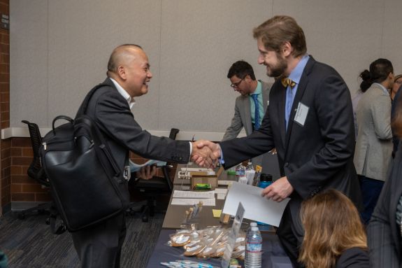 Two men in suits greet each other with a handshake