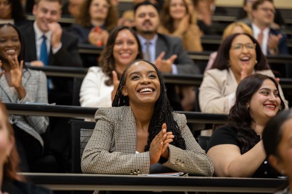 Seated students smile and clap in the Lecture Hall