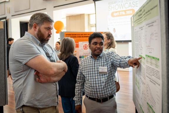 student presenting research on a posterboard