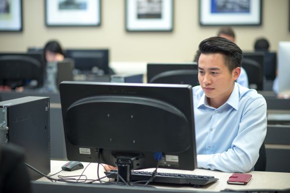 A student looks at a computer screen in a computer lab