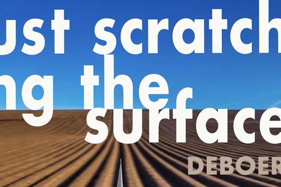 White letters on blue sky and dirt brown field