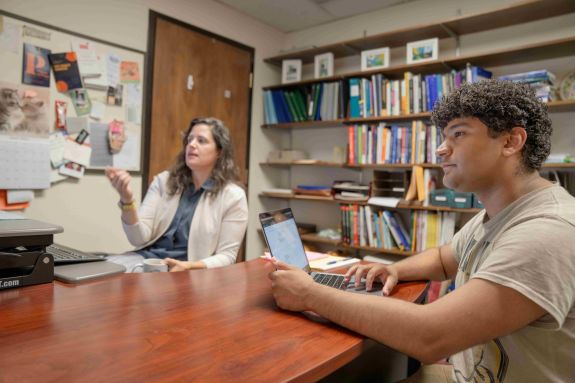 Student and professor are talking at a desk.