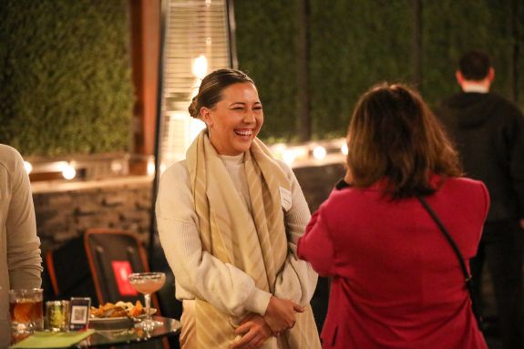 A woman smiles and laughs at an outdoor event