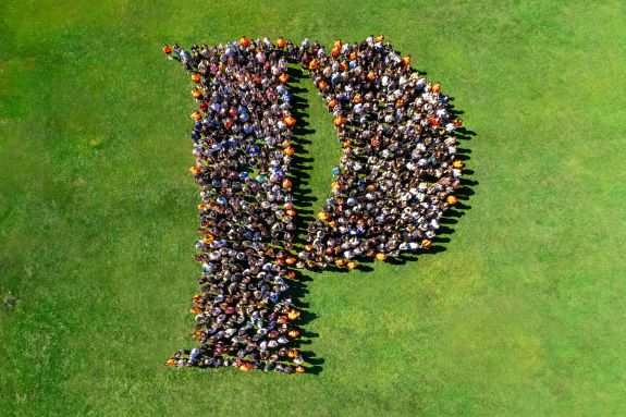 Students form the Pacific "P" on a grass lawn.