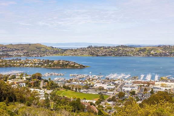 An overview shot of the Bay Area with a city in the foreground and blue water in the background. 