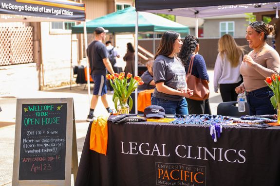A photo of an outdoor event withe the words "Legal Clinics" on the main table. 