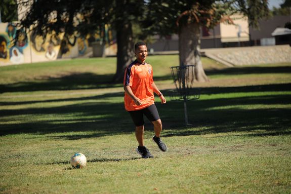 A man in an orange jersey plays soccer. 