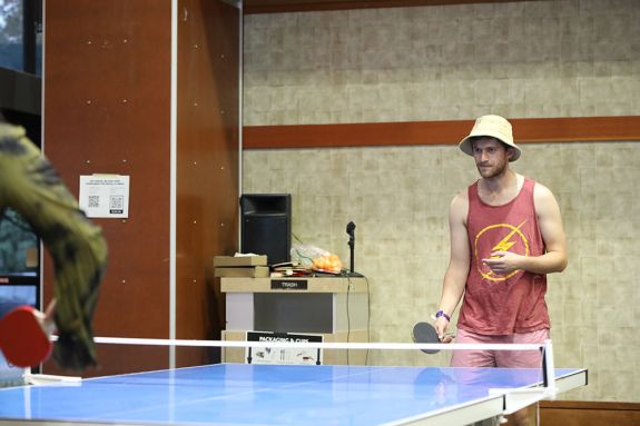 Two people playing table tennis in an indoor setting. 
