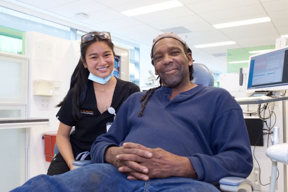 Woman dentist at the side of a dental chair with male black patient