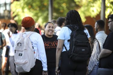 Three women stand in conversation.