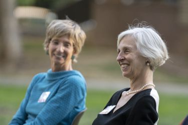 Three people who are seated smile 
