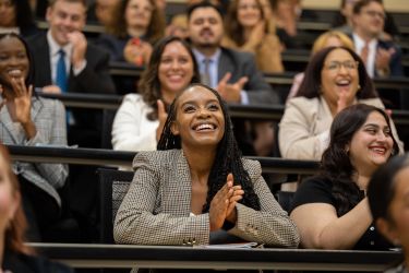 Seated students smile and clap in the Lecture Hall
