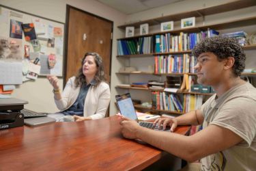 Student and professor are talking at a desk.