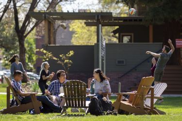 People outside on quad lawn laughing in lawn chairs 