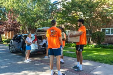 Students helping another student move in outside
