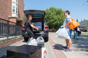 Student assisting in unloading a car with boxes