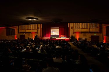 faye spanos concert hall with dim lighting and tedxuop logo on stage