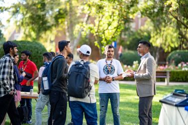 Students speaking with Dean Chaudhary on Knoles Lawn
