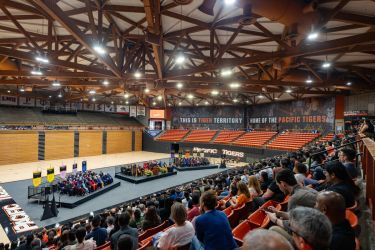 Students sitting in bleachers watching faculty on stage