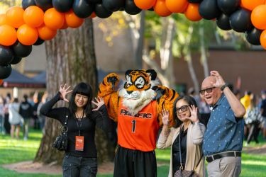 family posing with powercat under an orange and black balloon arch