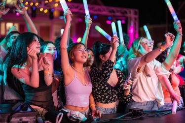 students attending a concert in the evening with bright lights