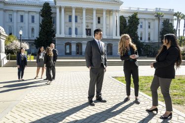 People smiling and laughing standing in front of the California State Capital Building