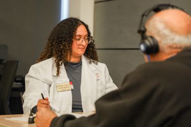 A student conducts a hearing screening with a patient.