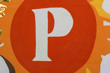 A colorful mural features a large red circle with a prominent white letter "P" in the center, surrounded by abstract yellow, white, and orange shapes.