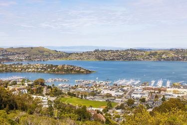 An overview shot of the Bay Area with a city in the foreground and blue water in the background. 