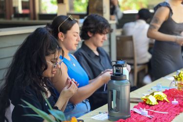 A group of students sit outside while working on origami. 
