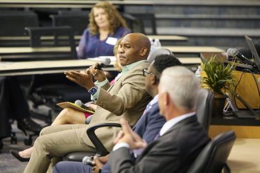 A panelist talks in a lecture hall. 