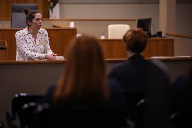 A woman specks to a group of students.