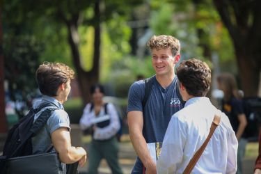 A group of students chat and smile. 