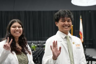 Two PharmD students waving and smiling at the camera
