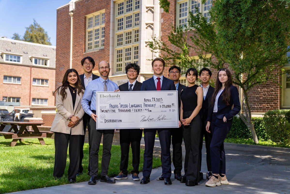 members of the student investment fund present a large check to a Pacific department
