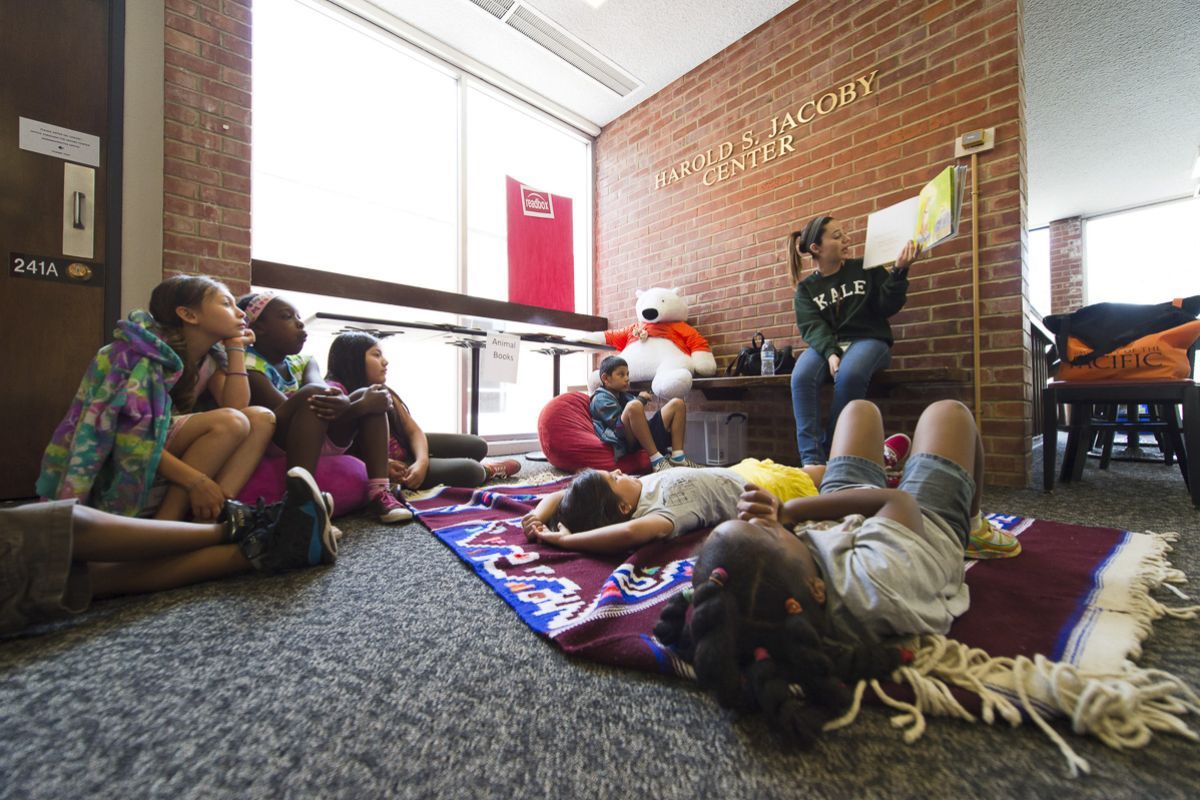 children participating in Pacific Summer Academy listen to a story being read at the Jacoby Center