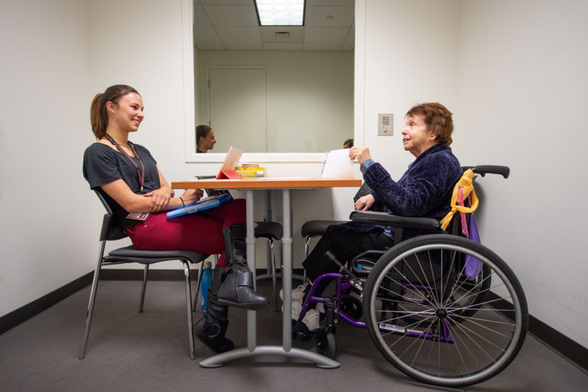 student talking to senior in wheelchair