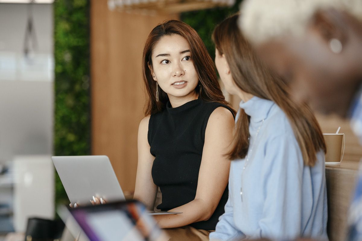 woman using laptop and talking to co-workers