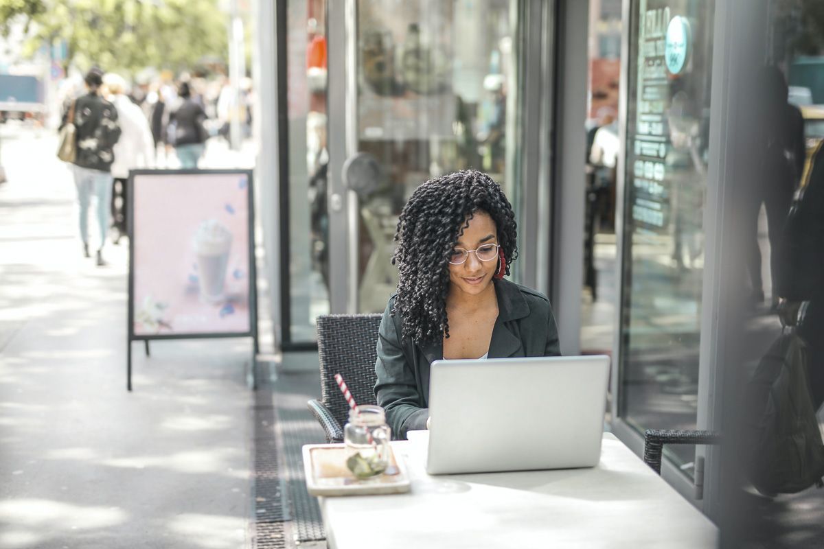 woman using laptop at sidewalk cafe