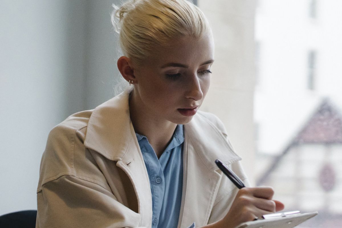 woman writing on clipboard in an office