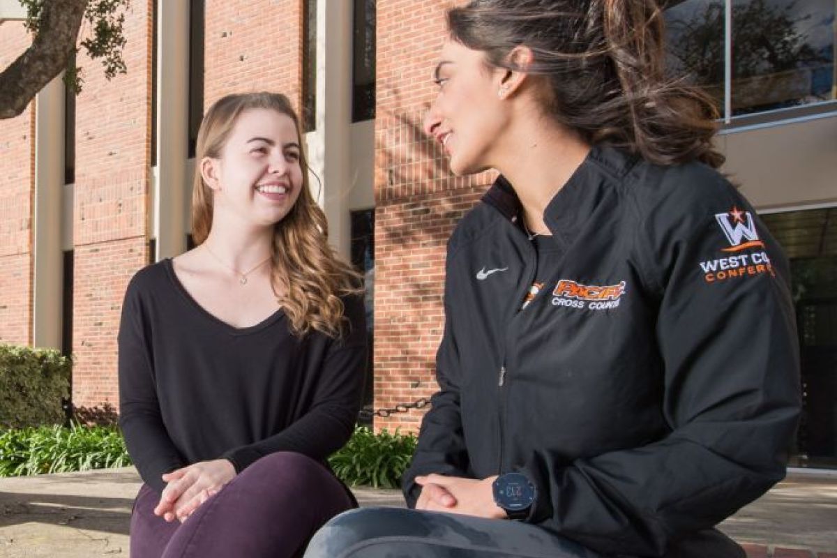 two students sitting on a ledge and talking