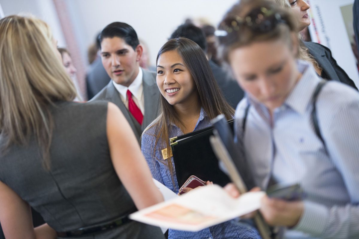 Graduate students meet with potential employers at a career resource center employer fair.