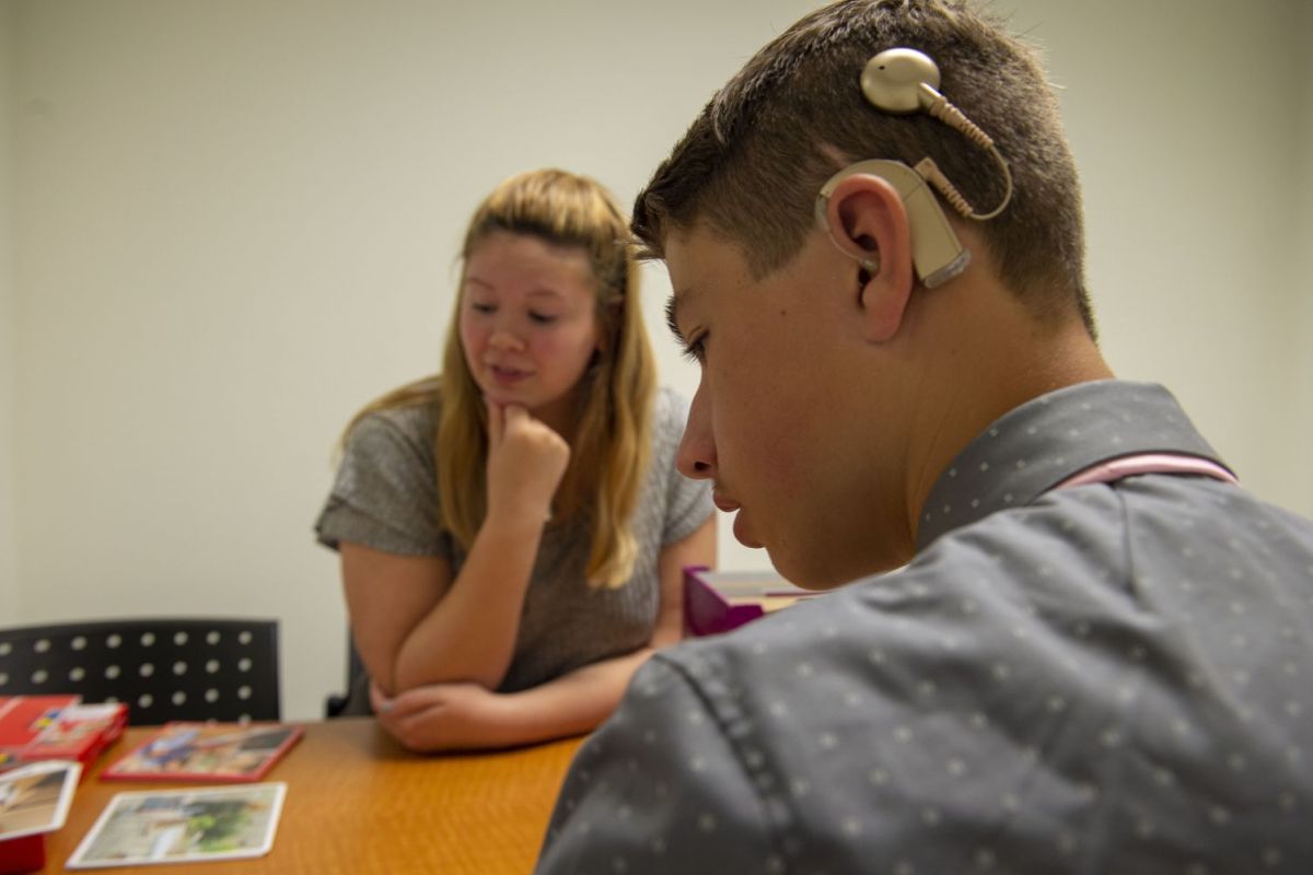 student working with someone that has a hearing aid on