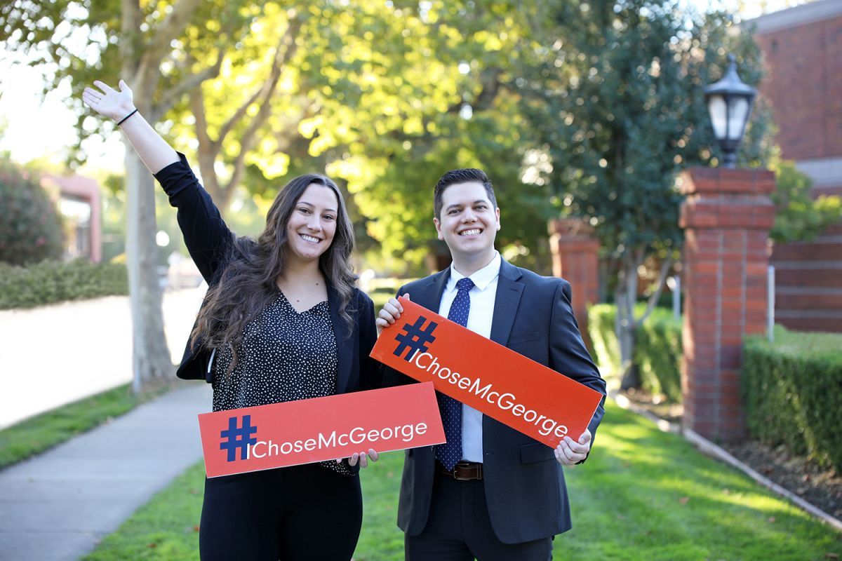 Two students holding small orange signs