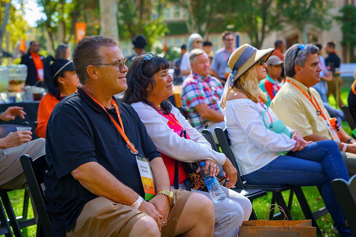 alumni listen to a presentation outdoors