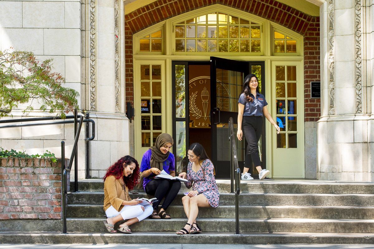 female students sit on the steps of Knoles Hall