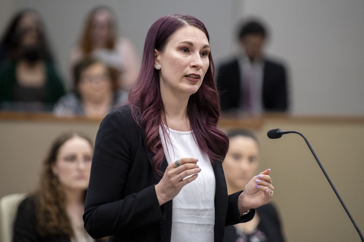 A law student stands at a podium in a courtroom.